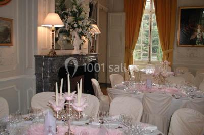 Façade d'un château en briques rouges et blanches avec un toit en ardoise, entouré d'un jardin bien entretenu.