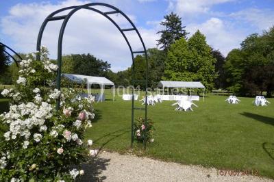 Façade d'un château en briques rouges et blanches avec un toit en ardoise, entouré d'un jardin bien entretenu.