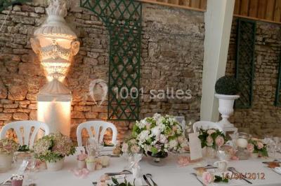 Façade d'un château en briques rouges et blanches avec un toit en ardoise, entouré d'un jardin bien entretenu.