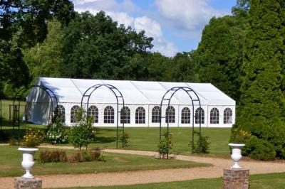 Façade d'un château en briques rouges et blanches avec un toit en ardoise, entouré d'un jardin bien entretenu.