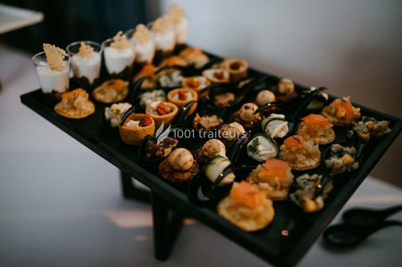 Plateau de canapés variés comprenant verrines, bouchées salées et amuse-bouches disposés sur une table.