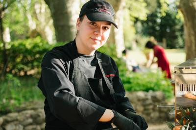Table dressée avec nappes blanches, verres à vin, couverts, petits pains et centre de table floral dans une salle lumineuse.