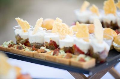 Miniature Traiteur Aix-en-Provence (Bouches-du-Rhône) - Carré Gourmand #5 Une mariée en robe blanche tient un bouquet dans une salle décorée pour un mariage, avec un homme en costume bleu derrière…