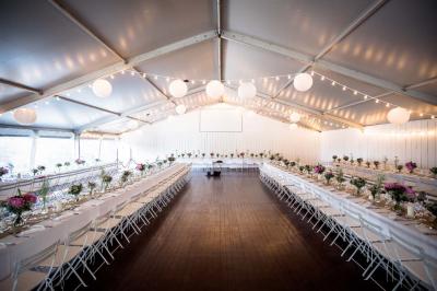 Miniature Traiteur Aix-en-Provence (Bouches-du-Rhône) - Carré Gourmand #9 Une mariée en robe blanche tient un bouquet dans une salle décorée pour un mariage, avec un homme en costume bleu derrière…