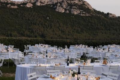 Miniature Traiteur Aix-en-Provence (Bouches-du-Rhône) - Carré Gourmand #16 Une mariée en robe blanche tient un bouquet dans une salle décorée pour un mariage, avec un homme en costume bleu derrière…