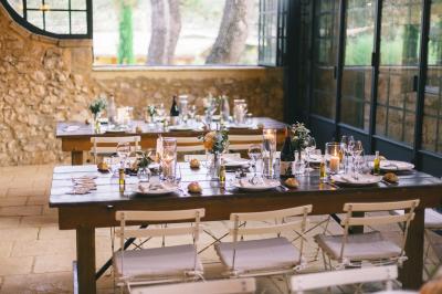 Miniature Traiteur Aix-en-Provence (Bouches-du-Rhône) - Carré Gourmand #20 Une mariée en robe blanche tient un bouquet dans une salle décorée pour un mariage, avec un homme en costume bleu derrière…