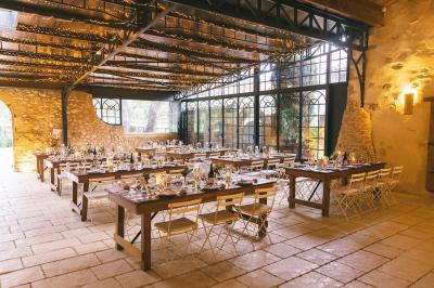 Miniature Traiteur Aix-en-Provence (Bouches-du-Rhône) - Carré Gourmand #21 Une mariée en robe blanche tient un bouquet dans une salle décorée pour un mariage, avec un homme en costume bleu derrière…