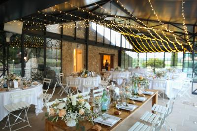 Miniature Traiteur Aix-en-Provence (Bouches-du-Rhône) - Carré Gourmand #30 Une mariée en robe blanche tient un bouquet dans une salle décorée pour un mariage, avec un homme en costume bleu derrière…