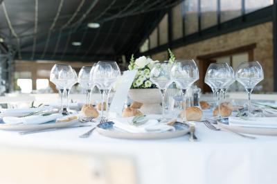 Miniature Traiteur Aix-en-Provence (Bouches-du-Rhône) - Carré Gourmand #33 Une mariée en robe blanche tient un bouquet dans une salle décorée pour un mariage, avec un homme en costume bleu derrière…
