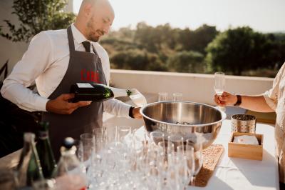 Miniature Traiteur Aix-en-Provence (Bouches-du-Rhône) - Carré Gourmand #34 Une mariée en robe blanche tient un bouquet dans une salle décorée pour un mariage, avec un homme en costume bleu derrière…