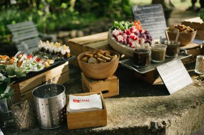 Miniature Traiteur Aix-en-Provence (Bouches-du-Rhône) - Carré Gourmand #35 Une mariée en robe blanche tient un bouquet dans une salle décorée pour un mariage, avec un homme en costume bleu derrière…