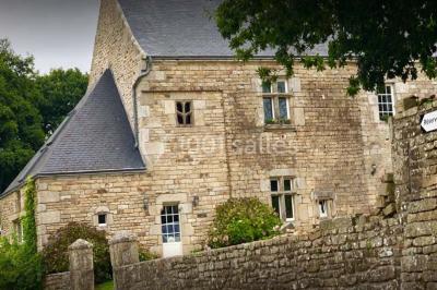 Terrasse extérieure avec tables et chaises en plastique sous une pergola, entourée de murs couverts de végétation.