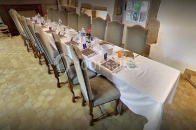 Terrasse extérieure avec tables et chaises en plastique sous une pergola, entourée de murs couverts de végétation.