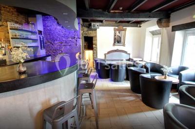 Terrasse extérieure avec tables et chaises en plastique sous une pergola, entourée de murs couverts de végétation.