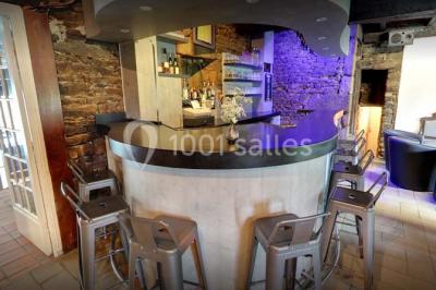 Terrasse extérieure avec tables et chaises en plastique sous une pergola, entourée de murs couverts de végétation.