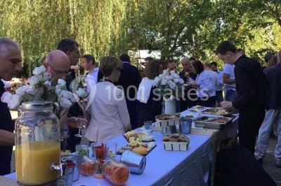 Chemin bordé d'arbres menant à un kiosque en bois avec un toit en tuiles, entouré de verdure.