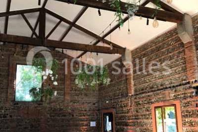 Chemin bordé d'arbres menant à un kiosque en bois avec un toit en tuiles, entouré de verdure.