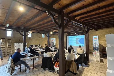 Chemin bordé d'arbres menant à un kiosque en bois avec un toit en tuiles, entouré de verdure.