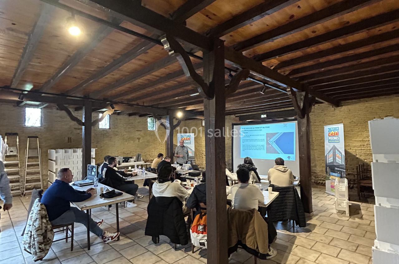 Des personnes assises dans une salle en bois assistent à une présentation projetée sur un écran.