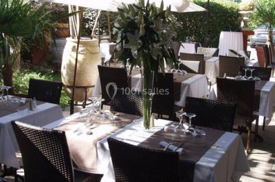 Table décorée avec une nappe blanche et rose, ornée de fleurs violettes et de plumes blanches, dans une salle festive.