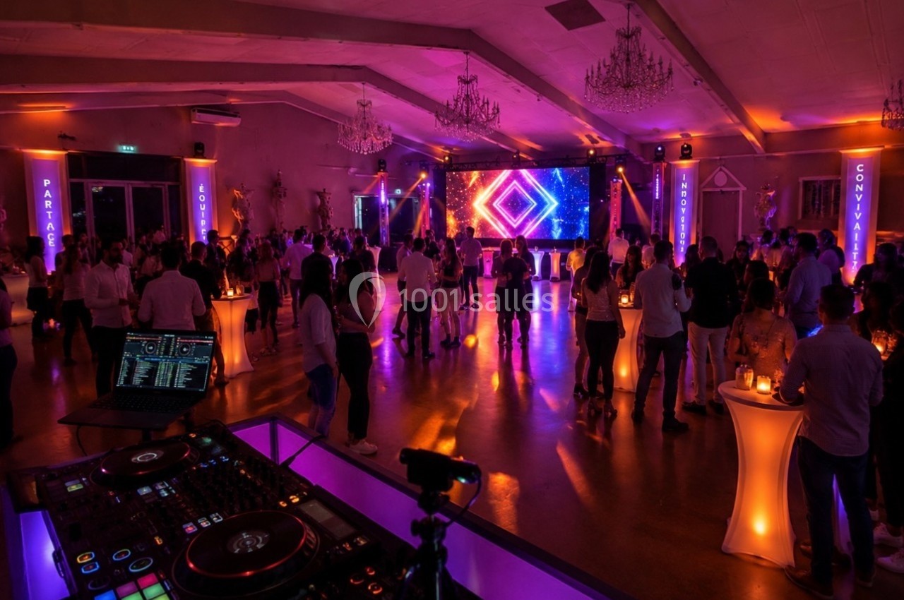Salle de réception animée avec des invités debout, une piste de danse éclairée et un DJ en arrière-plan.