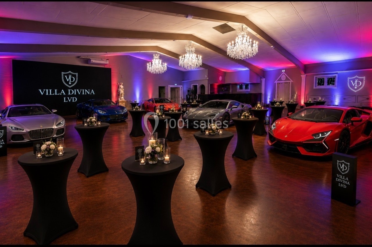 Salle élégante avec voitures de luxe exposées, éclairage coloré et tables hautes décorées de bougies et fleurs.
