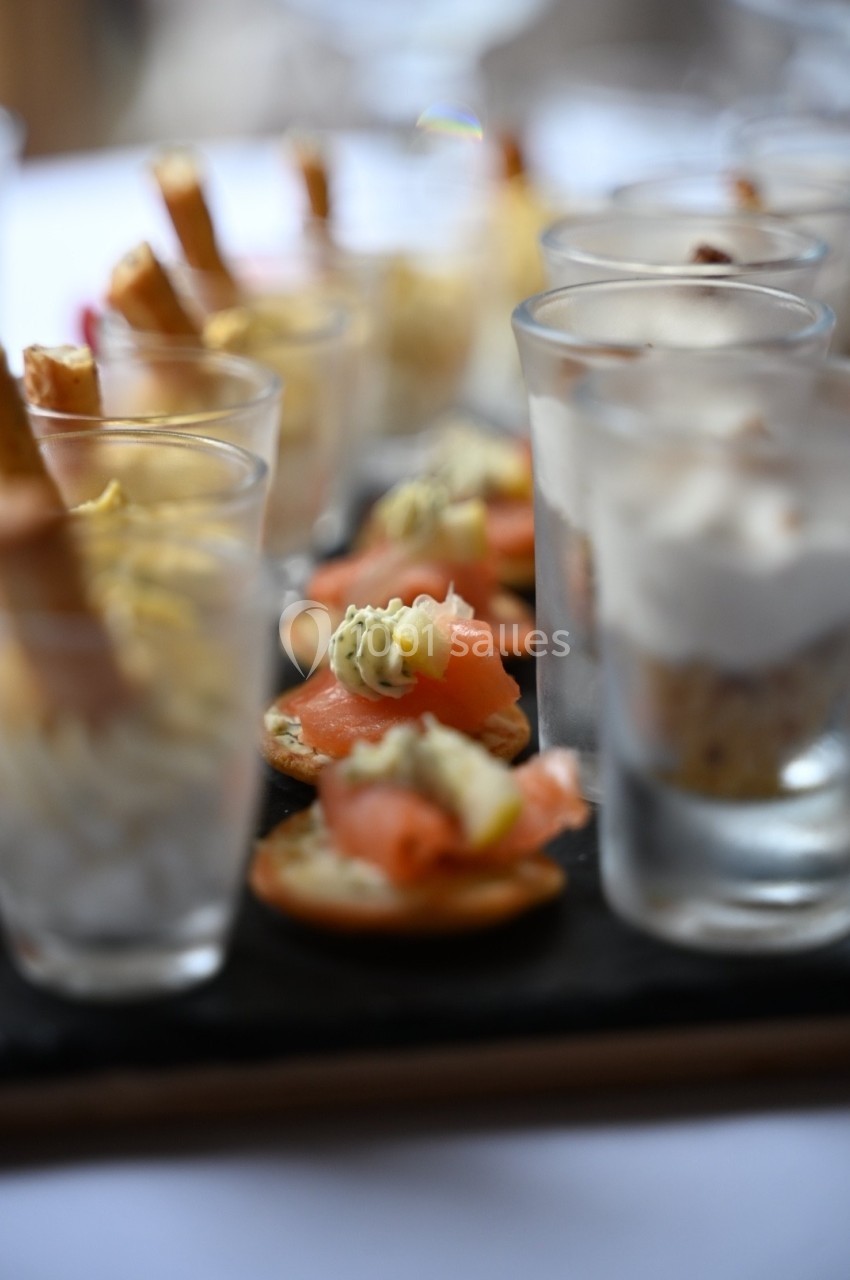 Plateau de verrines et amuse-bouches variés, disposés sur une ardoise pour un service élégant.