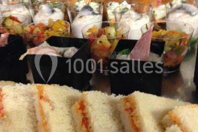 Salle de réception spacieuse avec tables hautes, chaises alignées, plantes décoratives et lustres suspendus.