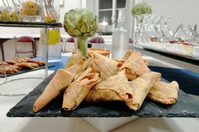 Manoir ancien entouré d'arbres, avec une pelouse en premier plan et un ciel clair en arrière-plan.