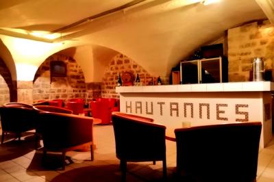 Manoir ancien entouré d'arbres, avec une pelouse en premier plan et un ciel clair en arrière-plan.