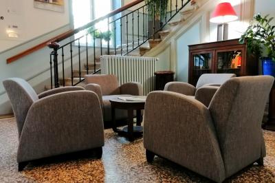 Manoir ancien entouré d'arbres, avec une pelouse en premier plan et un ciel clair en arrière-plan.