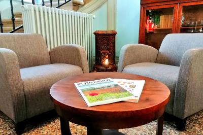 Manoir ancien entouré d'arbres, avec une pelouse en premier plan et un ciel clair en arrière-plan.