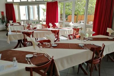 Manoir ancien entouré d'arbres, avec une pelouse en premier plan et un ciel clair en arrière-plan.