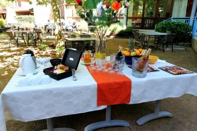 Manoir ancien entouré d'arbres, avec une pelouse en premier plan et un ciel clair en arrière-plan.