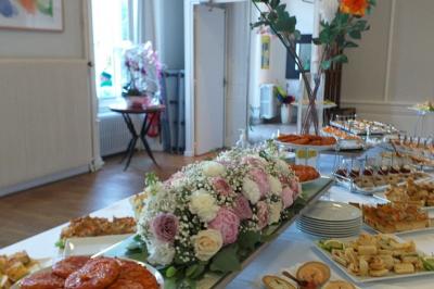 Manoir ancien entouré d'arbres, avec une pelouse en premier plan et un ciel clair en arrière-plan.