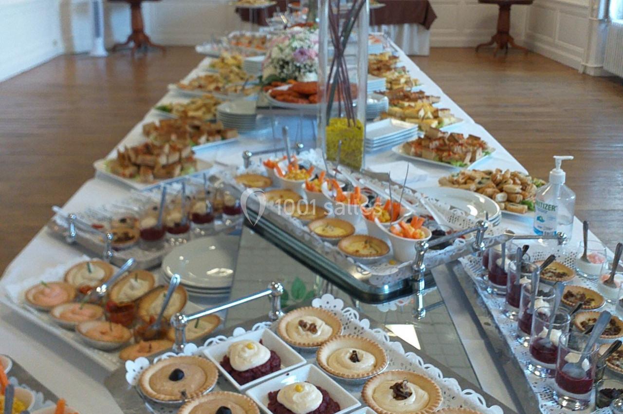 Buffet varié avec desserts, verrines, quiches et amuse-bouches disposés sur une grande table dans une salle lumineuse.