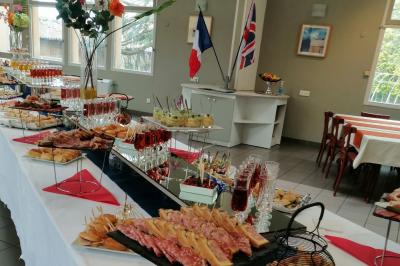 Manoir ancien entouré d'arbres, avec une pelouse en premier plan et un ciel clair en arrière-plan.