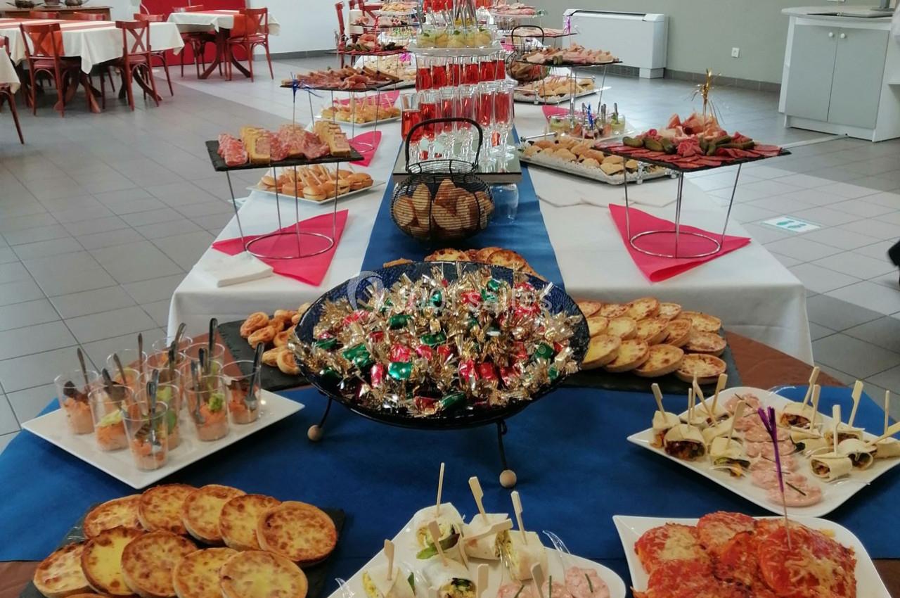 Buffet varié avec plats salés, verrines, amuse-bouches, pains et bonbons disposés sur une grande table.