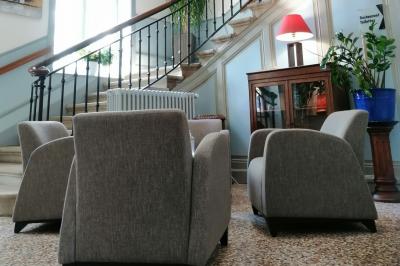 Manoir ancien entouré d'arbres, avec une pelouse en premier plan et un ciel clair en arrière-plan.