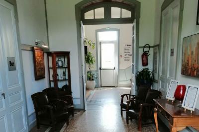 Manoir ancien entouré d'arbres, avec une pelouse en premier plan et un ciel clair en arrière-plan.