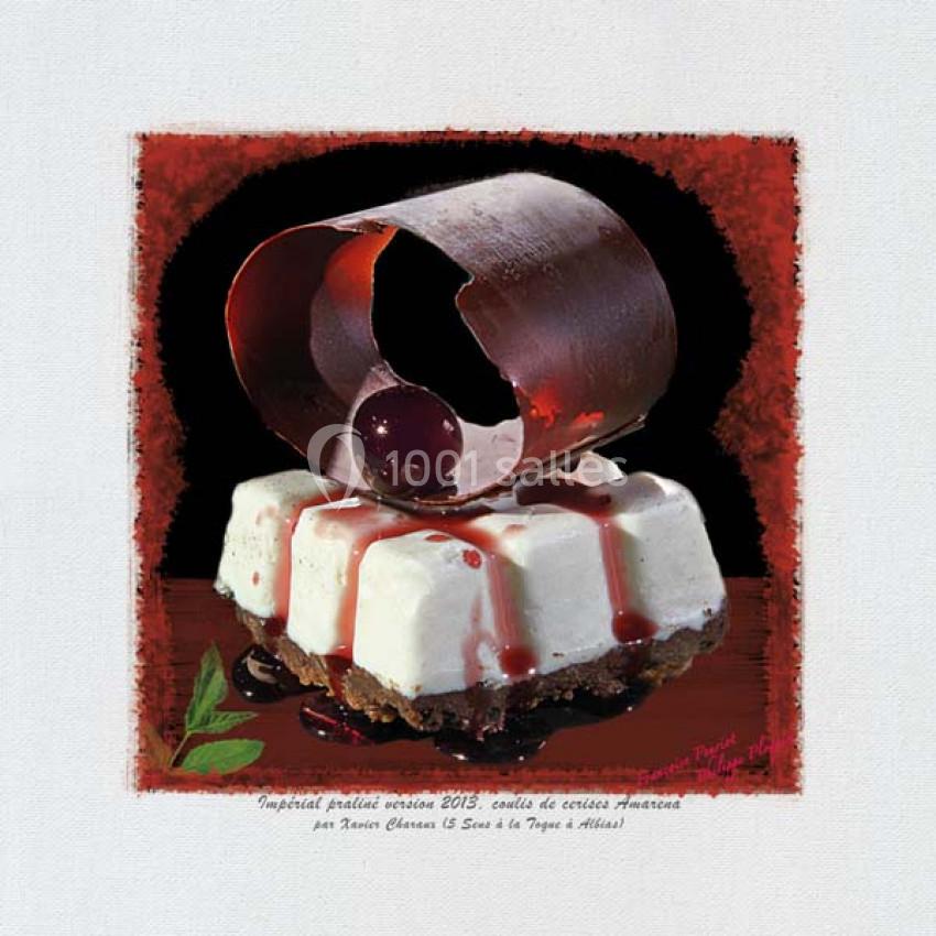 Dessert composé d'une base biscuitée, mousse blanche, cerise Amarena et décor en chocolat courbé.