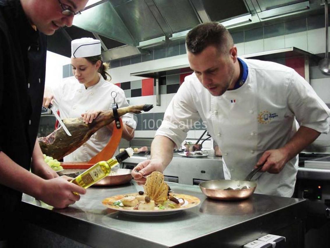 Un chef et son équipe préparent un plat gastronomique dans une cuisine professionnelle.