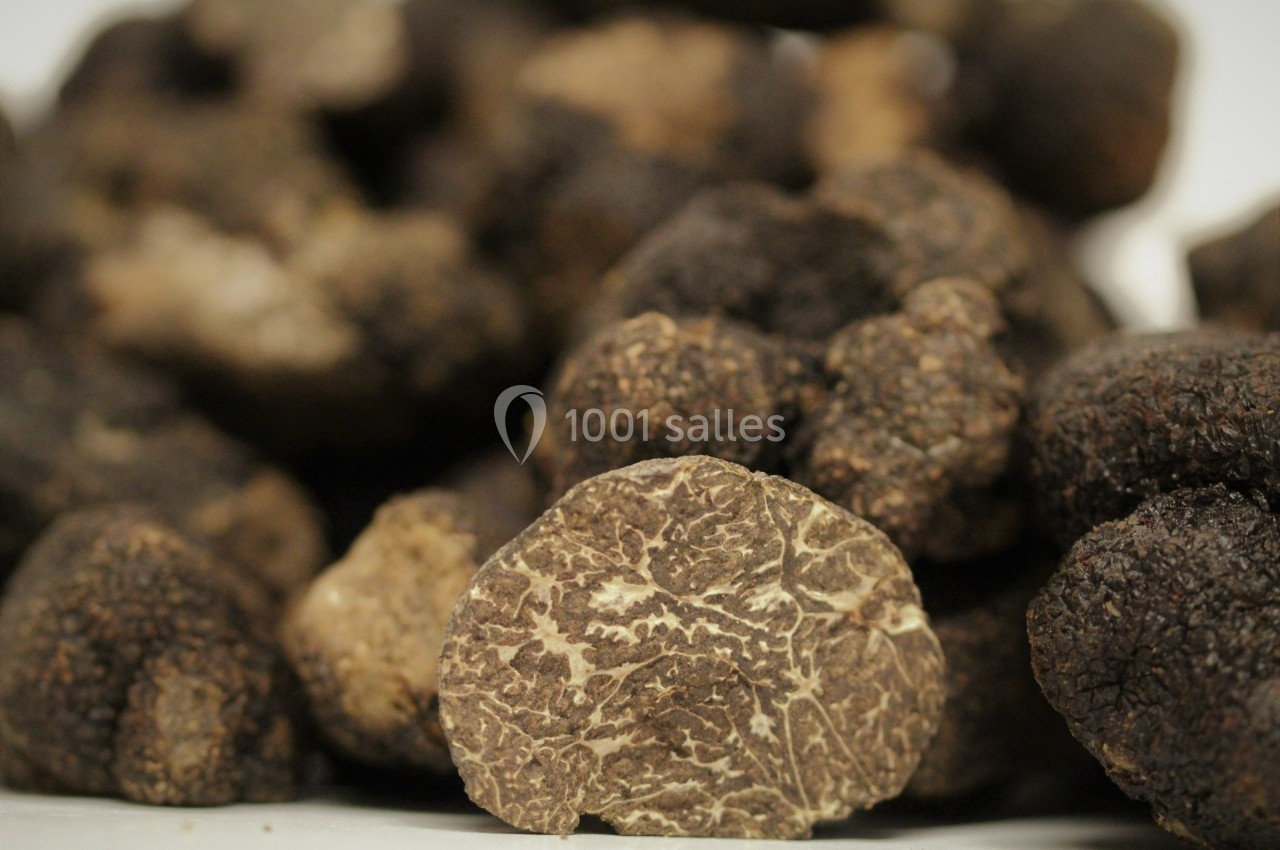 Truffes noires entières et une truffe coupée en deux montrant son intérieur veiné.