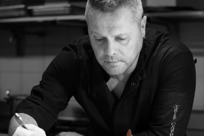 Miniature Traiteur Montauban (Tarn-et-Garonne) - 5 Sens A La Toque #33 Un chef pâtissier concentré décore un dessert coloré dans une cuisine professionnelle.