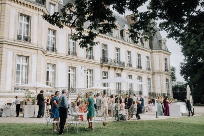 Manoir ancien entouré d'arbres et de buissons sous la neige, éclairé par une lumière hivernale douce.