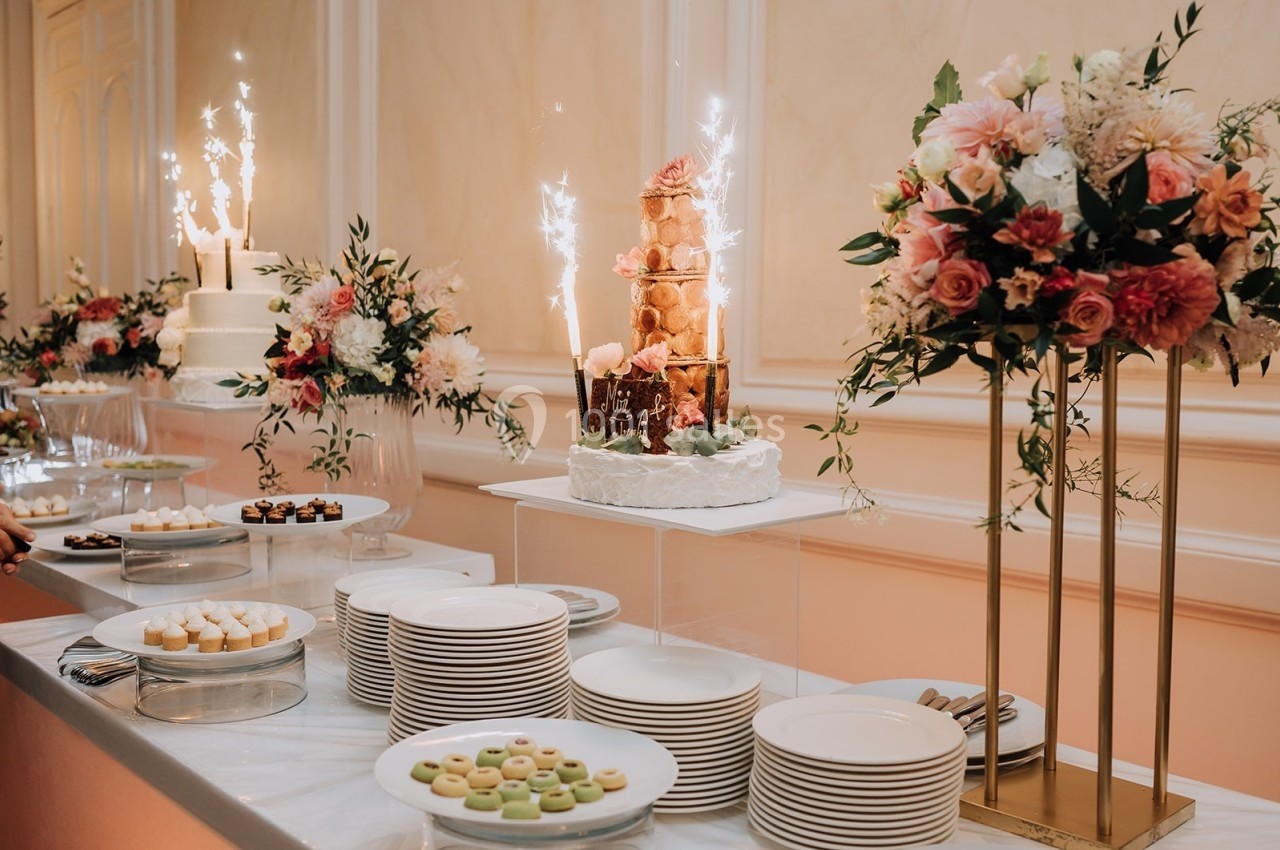 Table de buffet décorée avec des assiettes, des desserts variés et une pièce montée ornée de feux d'artifice.