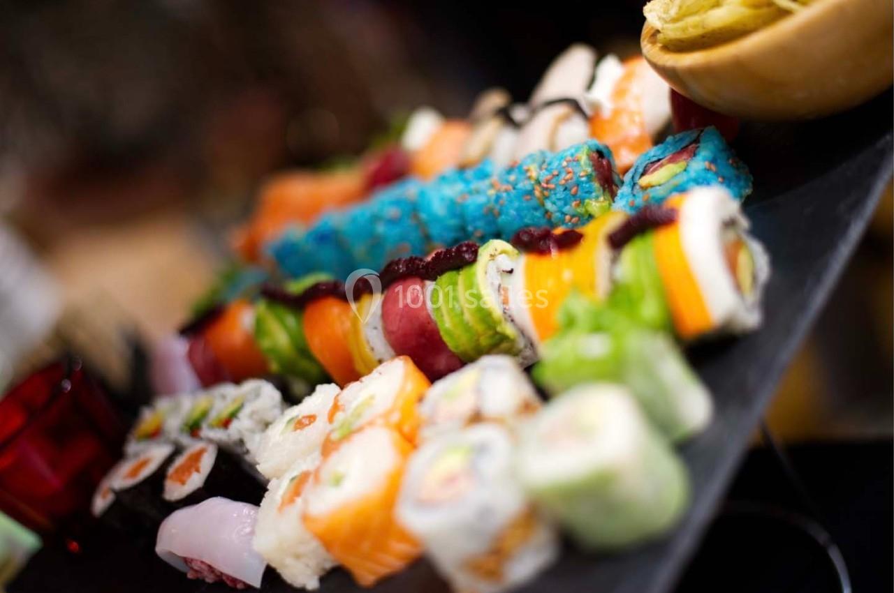 Assortiment coloré de sushis et makis variés disposés sur un plateau noir.