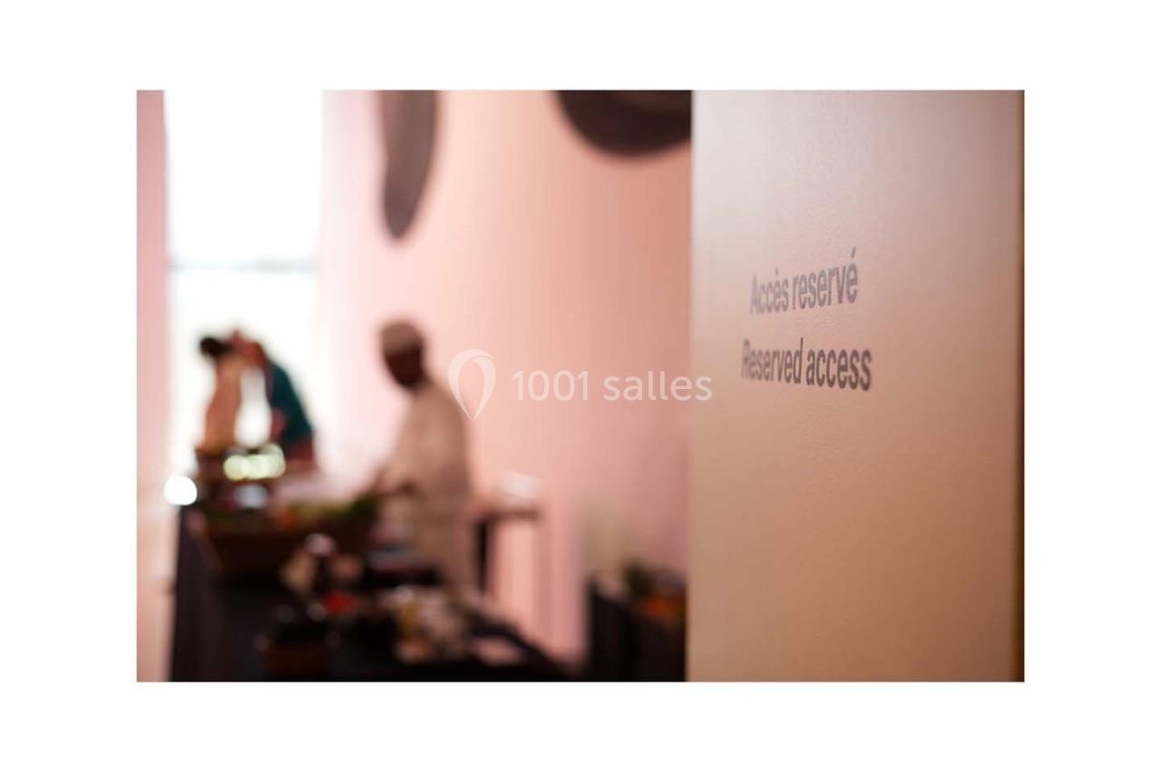 Inscription ’Accès réservé’ sur un mur, avec des silhouettes floues de personnes en arrière-plan dans un espace lumineux.