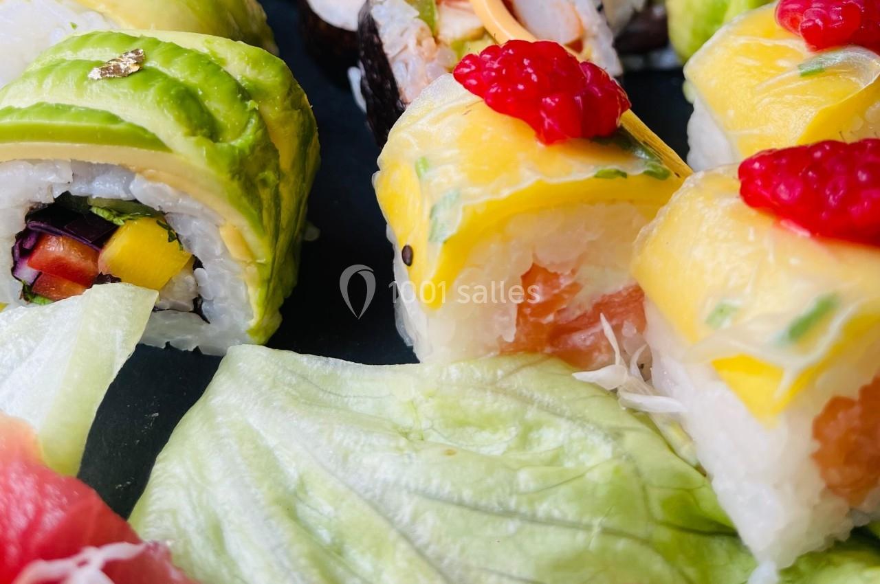 Assortiment de sushis colorés avec garnitures d'avocat, mangue et poisson, accompagnés de feuilles de salade.