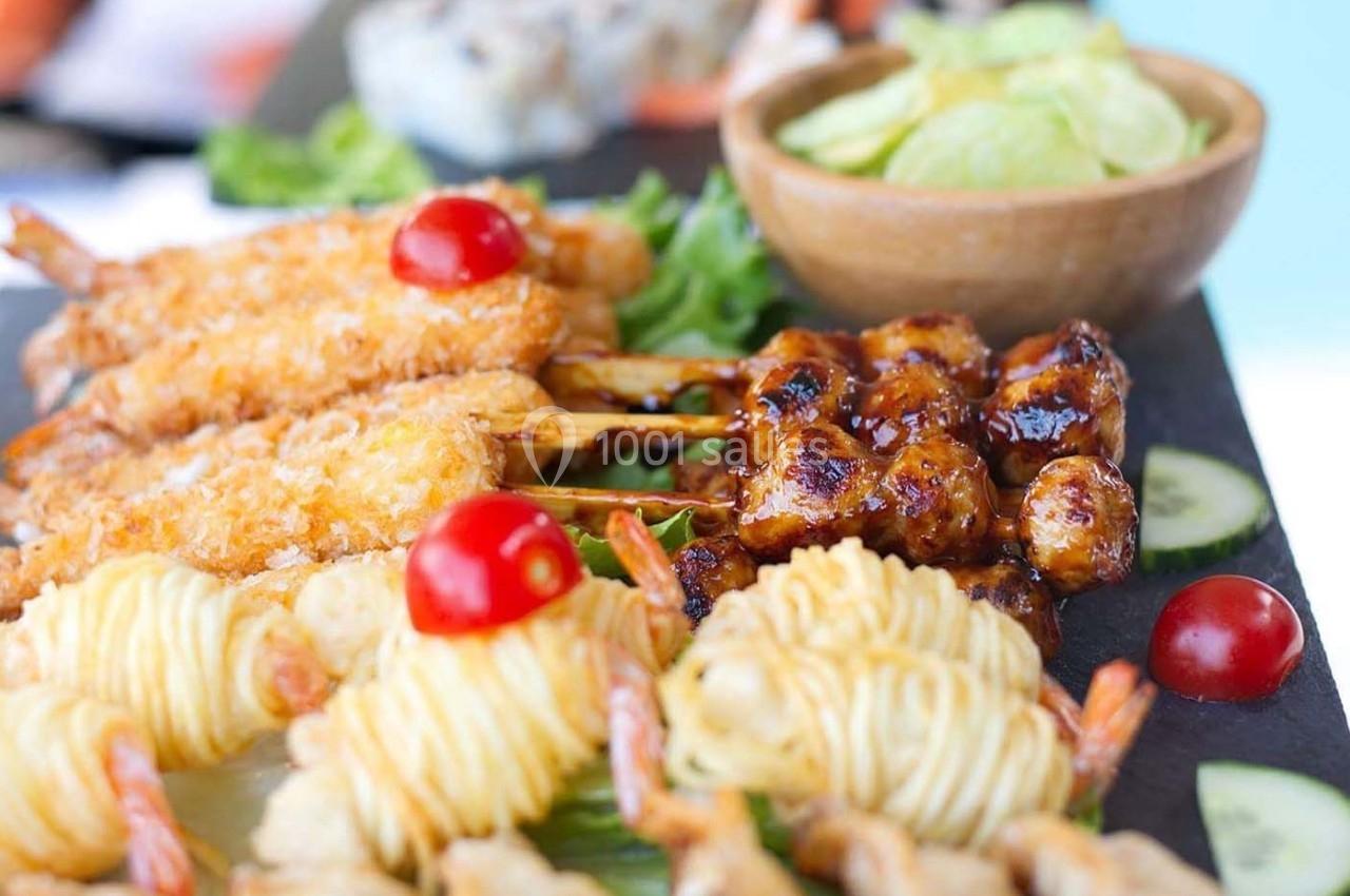 Assortiment de brochettes et bouchées apéritives avec crevettes, légumes et sauce, présenté sur un plateau.